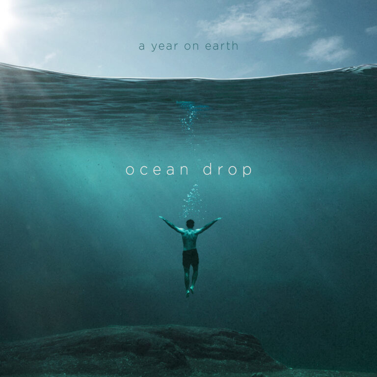 Image of A Year On Earth's "Ocean Drop" Album, released by THHmx. Showing a person floating beneath a calm body of water, with their arms up stretched and a light blue sky above and a greener aquamarine sheen in the water below.